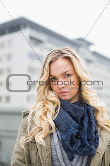 Unsmiling attractive blonde posing outdoors