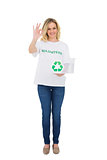 Smiling blonde volunteer holding recycling box making okay gesture