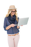 Smiling trendy blonde holding laptop