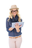 Smiling trendy blonde using tablet pc