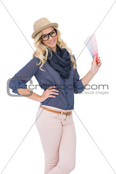 Smiling trendy blonde with classy glasses holding color chart