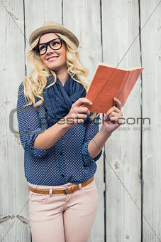 Cheerful fashionable blonde holding book outdoors
