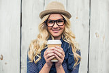 Cheerful fashionable blonde holding coffee outdoors