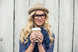 Pensive fashionable blonde holding coffee outdoors