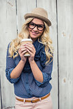 Happy trendy blonde holding coffee outdoors