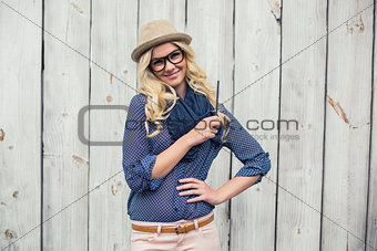 Cheerful trendy blonde holding pencil
