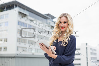 Smiling gorgeous blonde with red lips using tablet