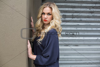 Unsmiling gorgeous blonde wearing classy dress posing outdoors