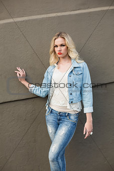 Stern casual blonde wearing denim clothes posing outdoors