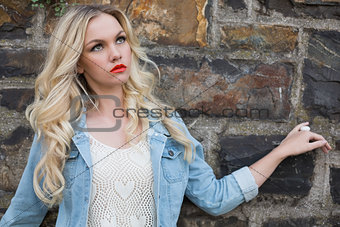 Day dreaming casual blonde wearing denim clothes posing outdoors