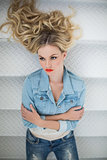Thinking blonde wearing denim clothes lying on stairs