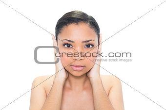 Serious young dark haired model covering her ears
