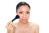 Pretty young dark haired model applying powder on her cheeks