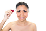 Happy young dark haired model applying mascara