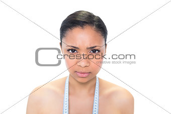 Upset young dark haired model wearing measuring tape around her neck