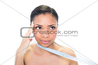 Thinking young dark haired model holding measuring tape