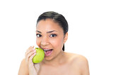 Playful young dark haired model eating a green apple