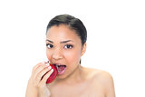 Cute young dark haired model eating a red apple
