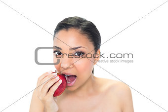 Cute young dark haired model eating a red apple