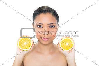 Relaxed young dark haired model holding orange halves