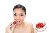 Relaxed young dark haired model eating strawberries