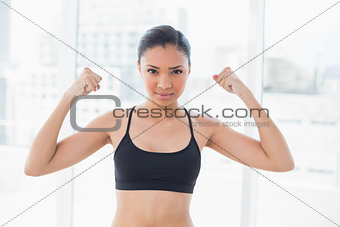 Dynamic dark haired model in sportswear showing her strength
