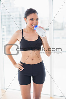 Pleased dark haired model in sportswear drinking water