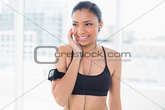 Pensive dark haired model in sportswear listening to music