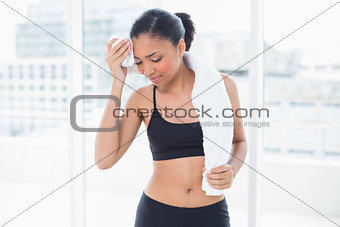 Tired dark haired model in sportswear drying herself with a towel