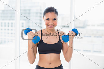 Motivated dark haired model in sportswear exercising with dumbbells