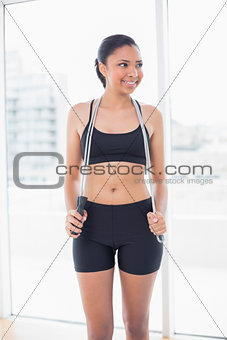 Cute dark haired model in sportswear holding a skipping rope