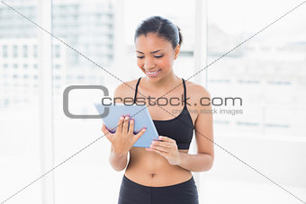 Concentrated dark haired model in sportswear using a tablet pc
