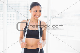 Happy dark haired model in sportswear holding a measuring tape