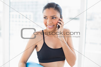 Pensive dark haired model in sportswear making a phone call