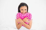 Delighted young dark haired model cuddling a heart-shaped pillow