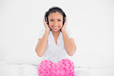 Cheerful young dark haired model listening to music with headphones