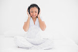 Peaceful young dark haired model listening to music with headphones