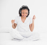 Happy young dark haired model listening to music with headphones