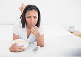 Peaceful young dark haired model eating popcorn while watching tv
