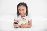 Charming young dark haired model holding a mobile phone and a plush sheep