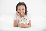 Joyful young dark haired model making phone call while cuddling plush sheep