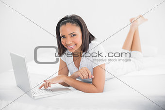 Pleased young dark haired model using a laptop