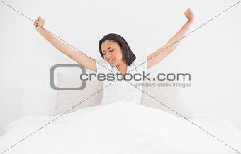 Exhausted young dark haired model stretching in her bed