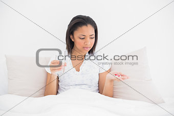 Worried young dark haired model taking medication