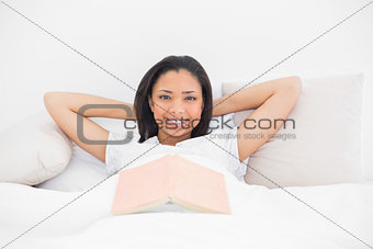 Smiling young dark haired model relaxing in her bed