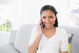 Happy young dark haired woman in white clothes making a phone call