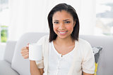 Joyful young dark haired woman in white clothes holding a mug