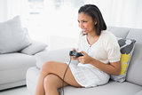 Delighted young dark haired woman in white clothes playing video games