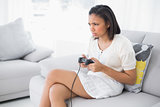 Frowning young dark haired woman in white clothes playing video games