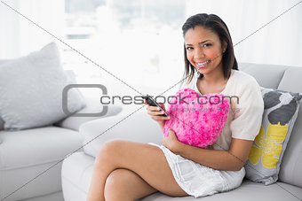 Pleased young dark haired woman in white clothes using a mobile phone